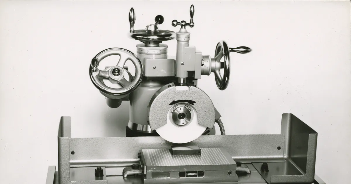 Surface grinding machine with a flat grinding wheel over the table, historic photo of the machine type used for grinding tungsten heavy alloy faces