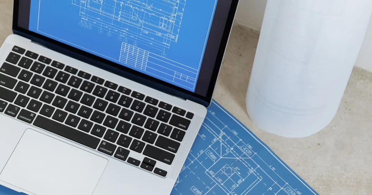 Laptop beside a printed technical drawing, as used when checking a drawing callout such as MIL-T-21014